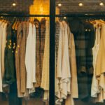 High end designer fashion display with luxury clothing on wooden hangers in a stylish boutique window.