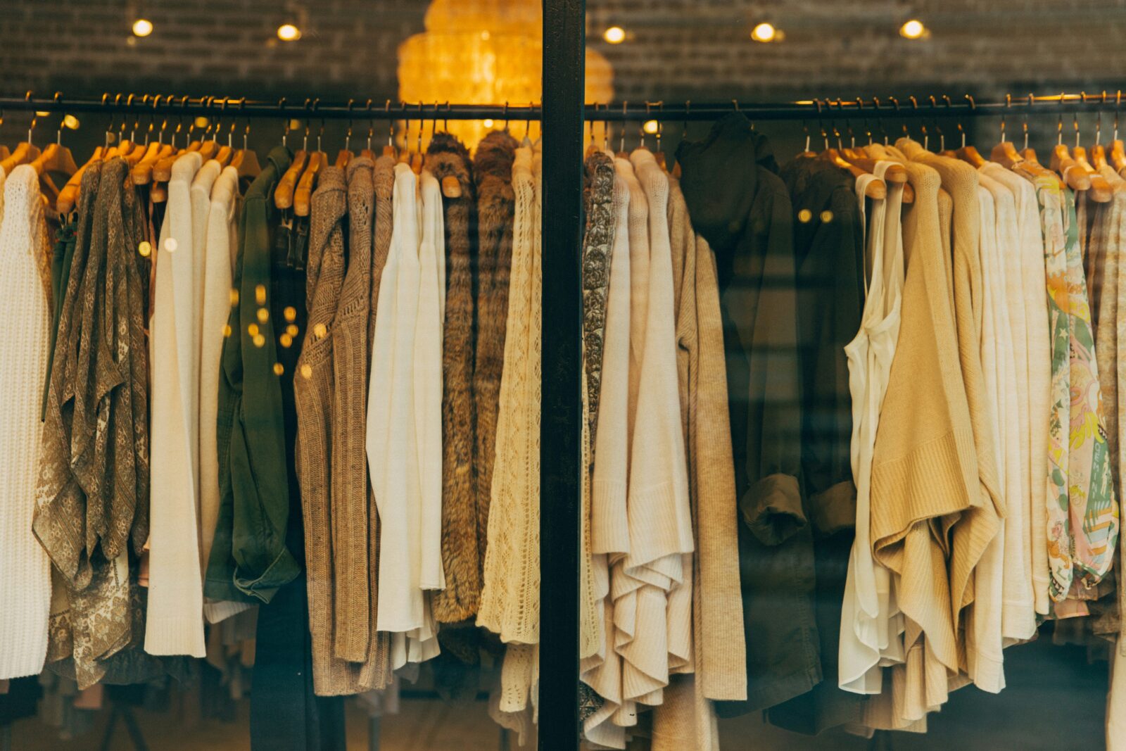 High end designer fashion display with luxury clothing on wooden hangers in a stylish boutique window.