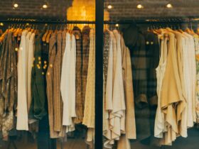 High end designer fashion display with luxury clothing on wooden hangers in a stylish boutique window.