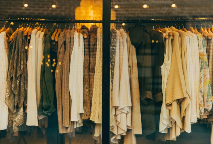 High end designer fashion display with luxury clothing on wooden hangers in a stylish boutique window.