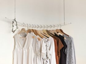Minimalist clothing rack with branded clothes womens in neutral tones on wooden hangers.