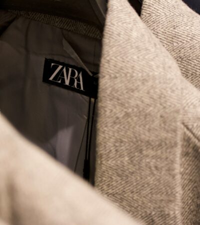 Is Zara fast fashion — close-up of Zara label on tweed jacket in clothing rack