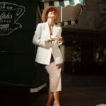 Woman in white blazer and beige skirt holding coffee showing the old money aesthetic style