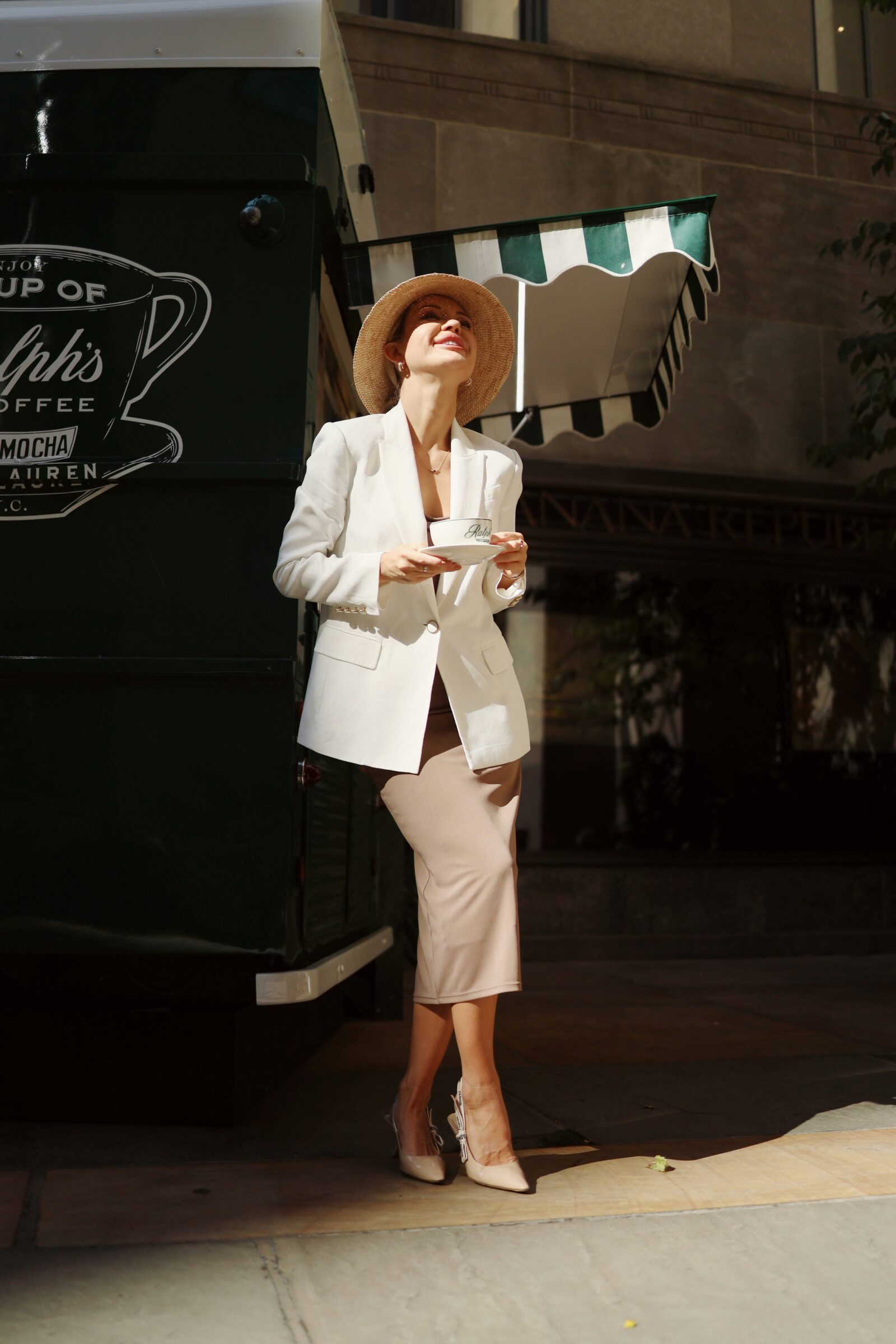 Woman in white blazer and beige skirt holding coffee showing the old money aesthetic style